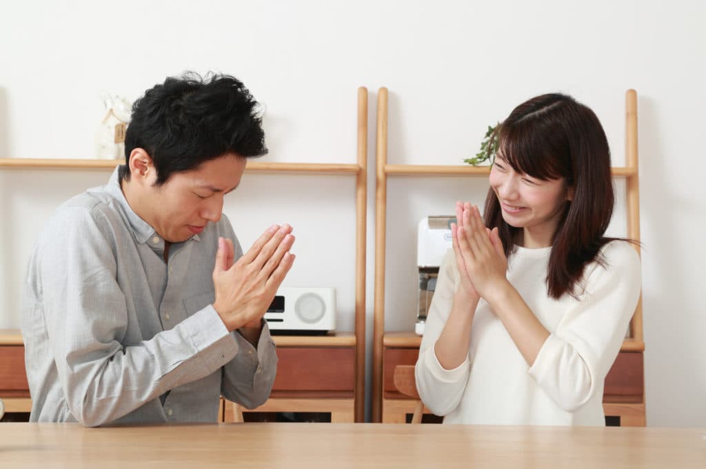 お互いに手を合わせて謝るカップル──ごめんねの一言