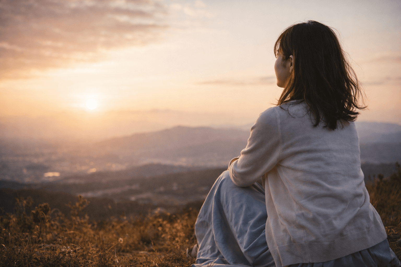 山の上から夕陽を見つめる──まだ終わりじゃない